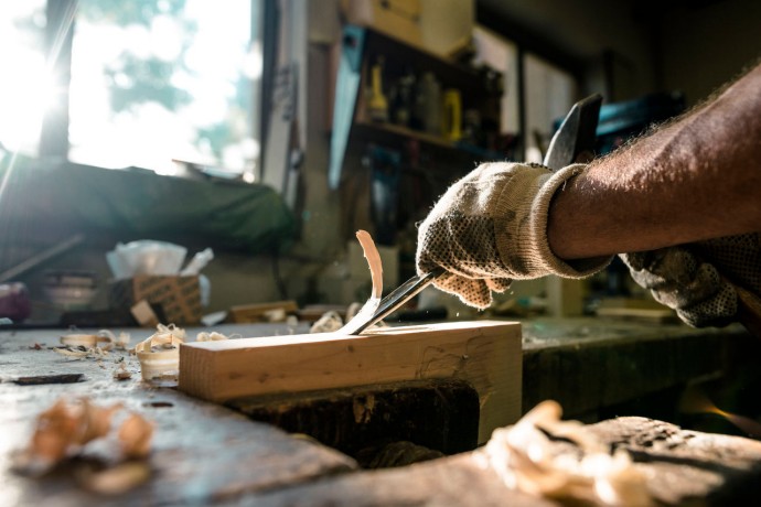 An experienced carpenter shapes wood with a chisel