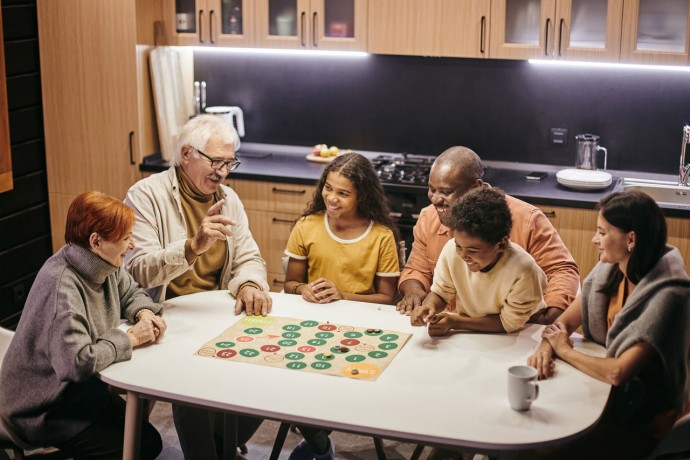 Large happy multiracial family playing board game by table